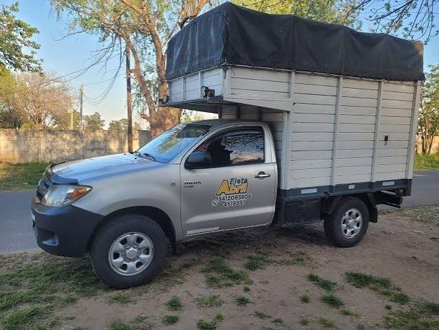 Camioneta gris con caja cerrada y lona, preparada para un flete.