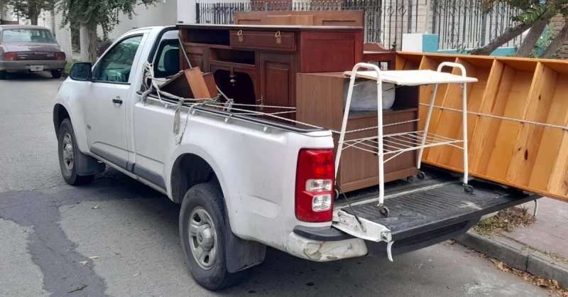 Camioneta blanca con muebles y estructuras cargadas para envío.